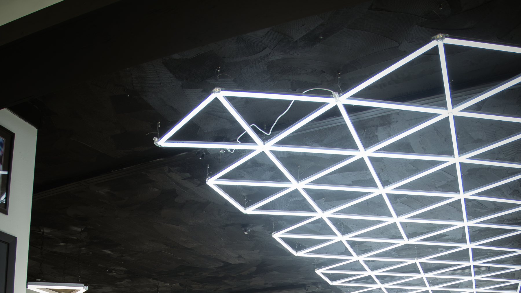 The hexagonal LED ceiling grid running the length of the shop floor