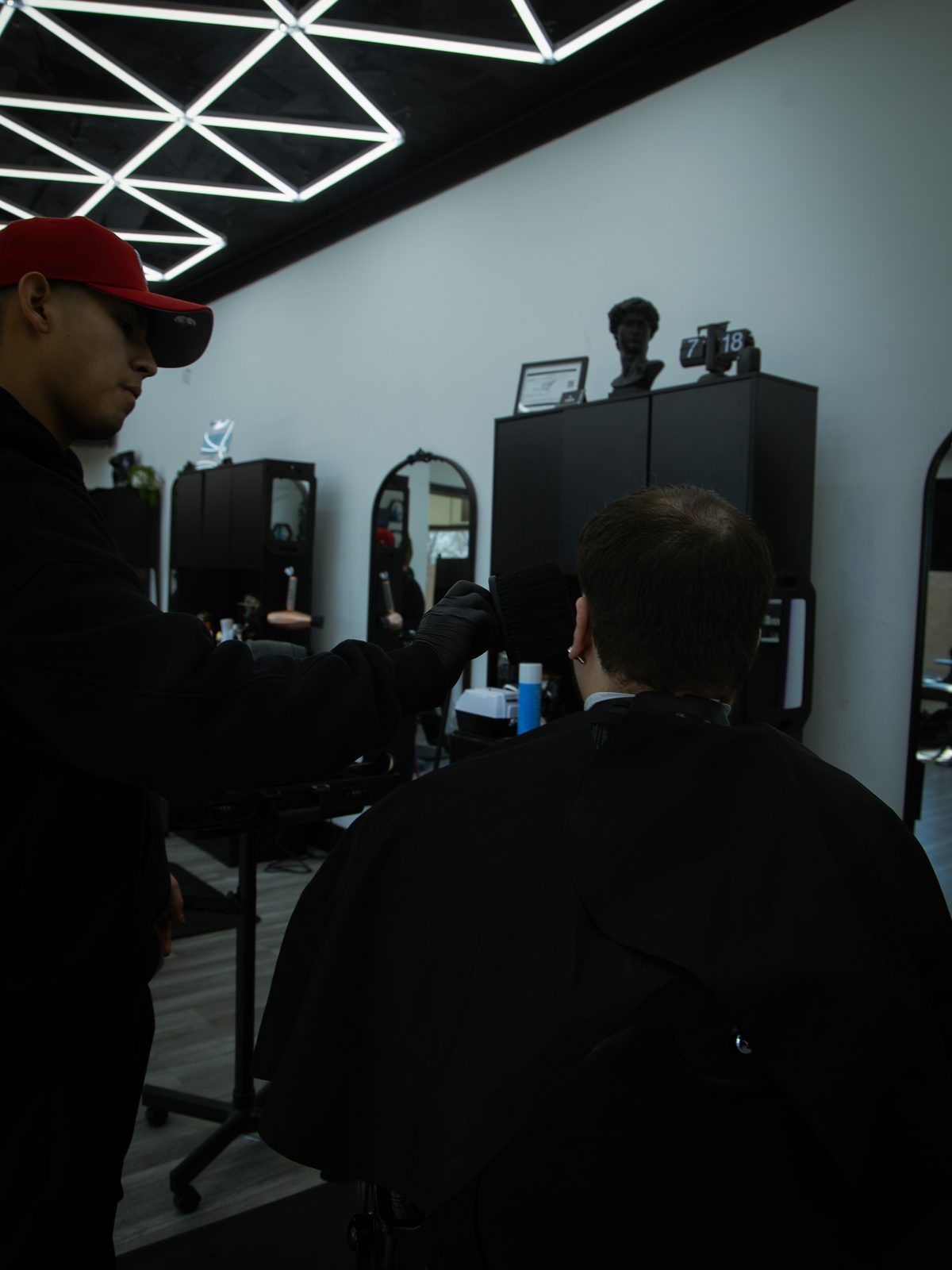 An owner working at the chair, the shop mirrors and sculpture behind